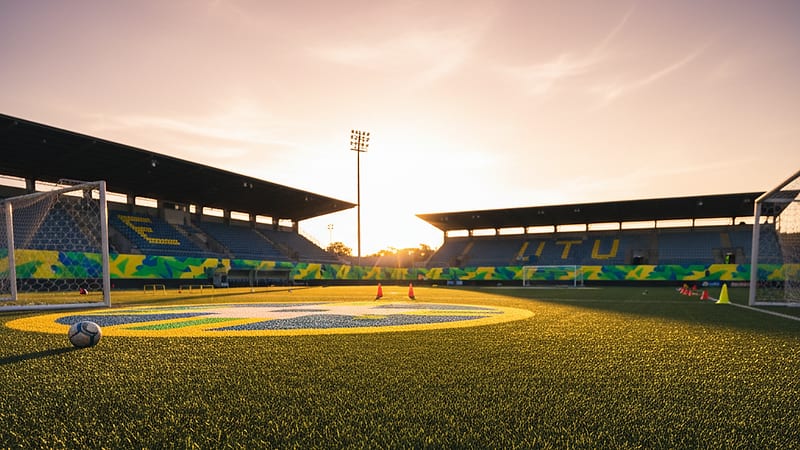Campo de treinamento vazio ao entardecer com bandeiras verde e amarela