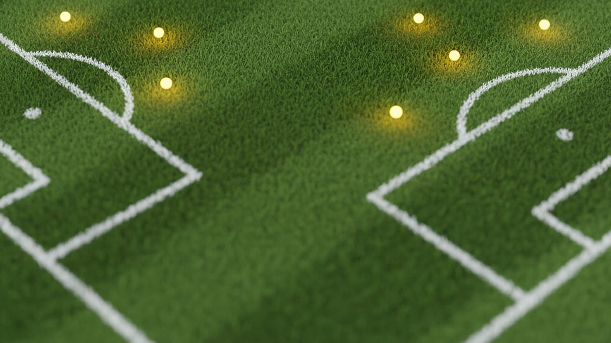 Campo de futebol de grama verde com linhas brancas e pontos de luz amarela no centro e perto das áreas.